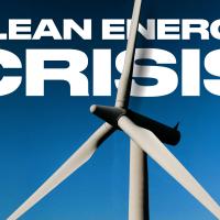 Wind turbine against a clear blue sky with bold white text reading "Clean Energy Crisis" in the background.