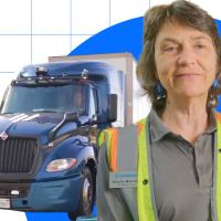 A woman is standing next to a semi truck.