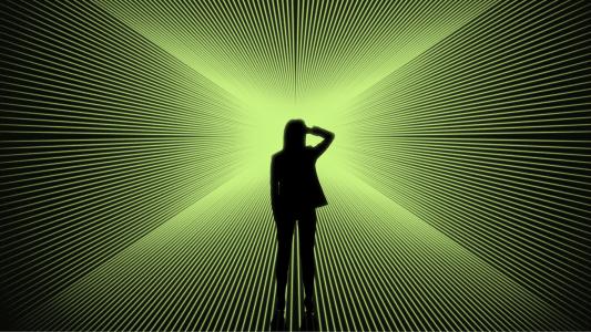 Silhouette of a person standing in front of a bright green, radial light pattern creating an optical illusion effect.