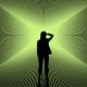 Silhouette of a person standing in front of a bright green, radial light pattern creating an optical illusion effect.