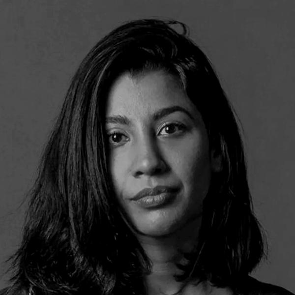 A woman with straight, shoulder-length dark hair looks directly at the camera with a neutral expression against a plain background.