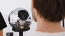 A silver spherical device on a stand, complete with a camera lens capturing a person. Reflections reveal the room's walls and furniture, lending an air of mystery akin to safeguarding one's personhood credentials.